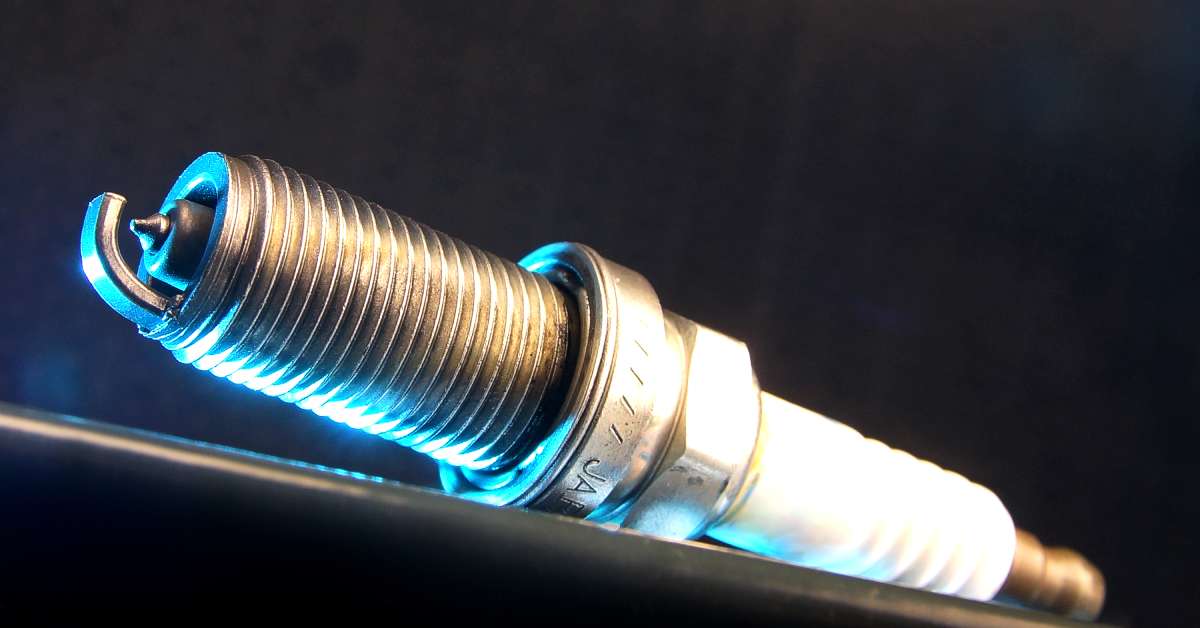 A full profile of a new platinum or iridium-tipped automotive spark plug isolated against a black background.