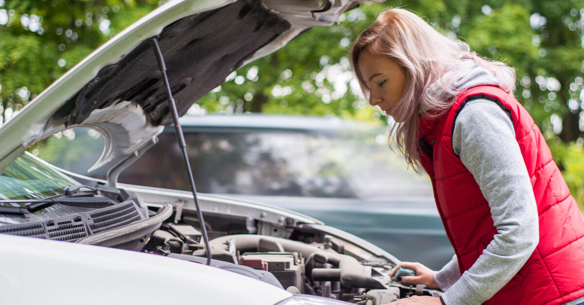 A young woman stopped by the roadside, examining her engine for signs of trouble with the hood raised.