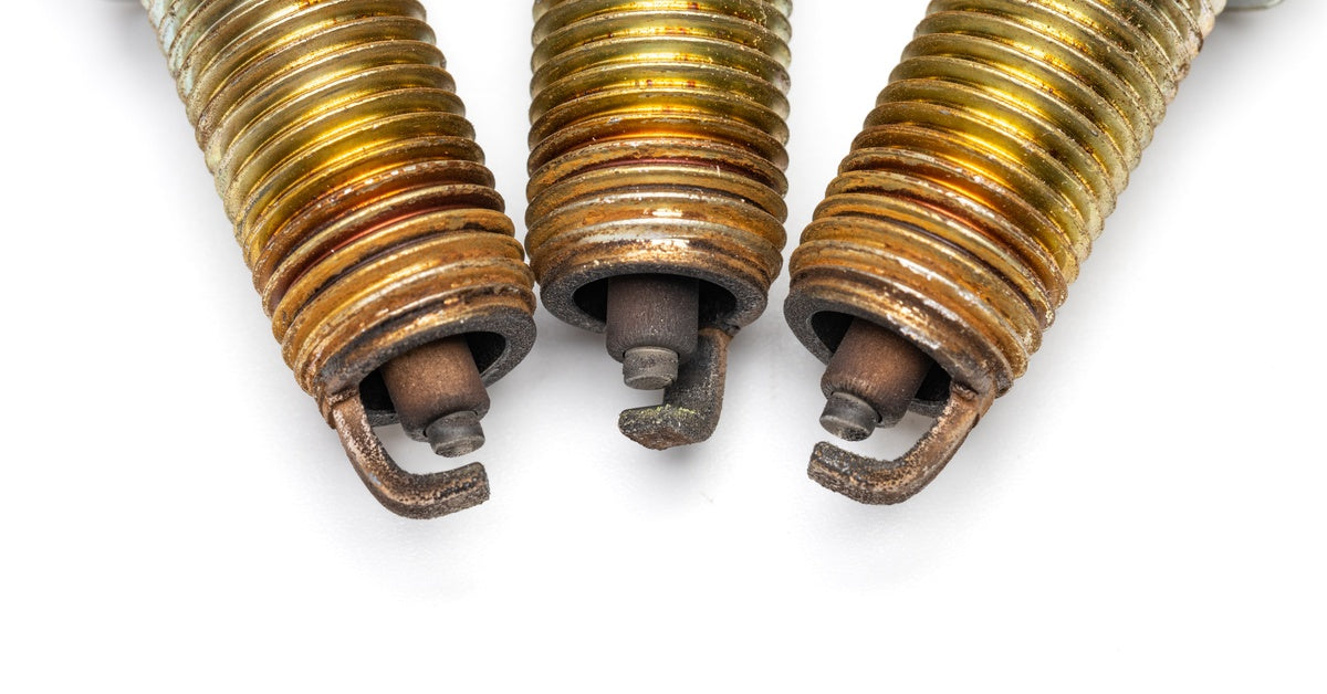 A close-up view of three used spark plug tips. They show signs of corrosion around the electrodes and grooves.