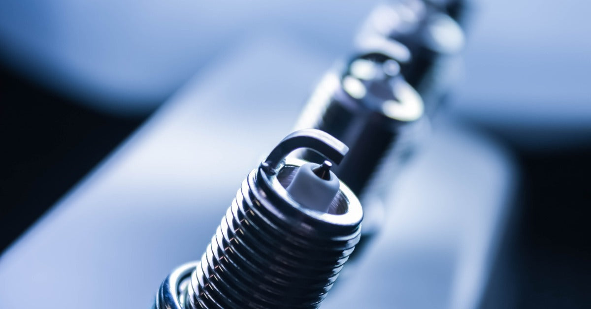 A close-up of four spark plugs that reflect light from the environment, creating shadows that enhance contrast.