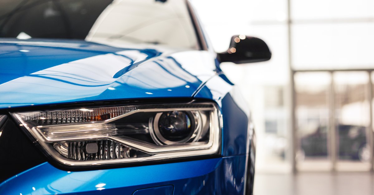A close-up view of a blue, modern vehicle headlight with reflective surfaces and lighting details visible.