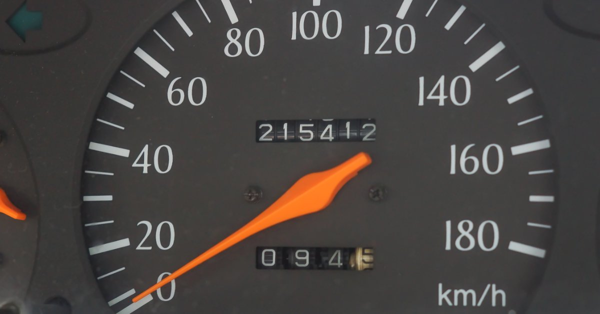 A close-up of a car dashboard shows an odometer reading of 200,000 kilometers next to a speedometer dial.