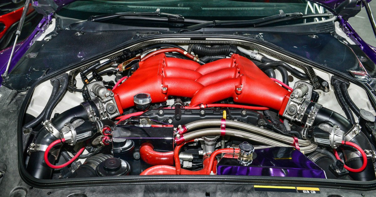 An open hood showcases a high-performance engine in a muscle car equipped with modified components and systems.