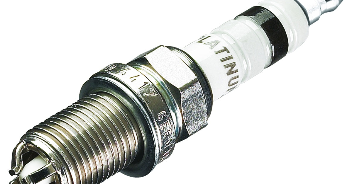 A close-up of a spark plug on a white background, with the word "platinum" written around its ceramic insulator.