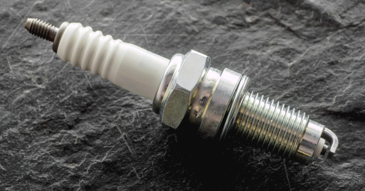 An extreme close-up of a spark plug with pristinely clean areas around the insulator, electrode, and terminal.